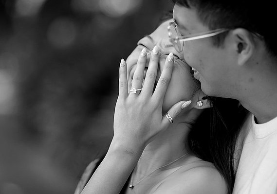 Black and white images of male and female laughing with females hand in front of her face showing her engagement ring