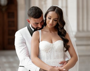 Groom hugging bride from behind kissing her shoulder. 