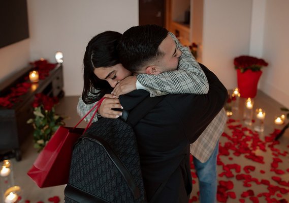Man and Woman hugging, candle and red roses, petals in background.