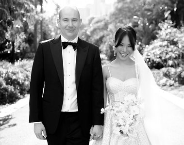 black and white photo of bride and groom walking towards camera in park setting. 