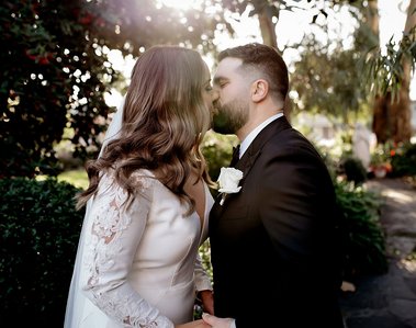 Bride and groom kissing in a park area