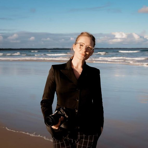 A portrait of Melbourne Wedding Photographer Jessica Abby posing with camera in hand on a beach.