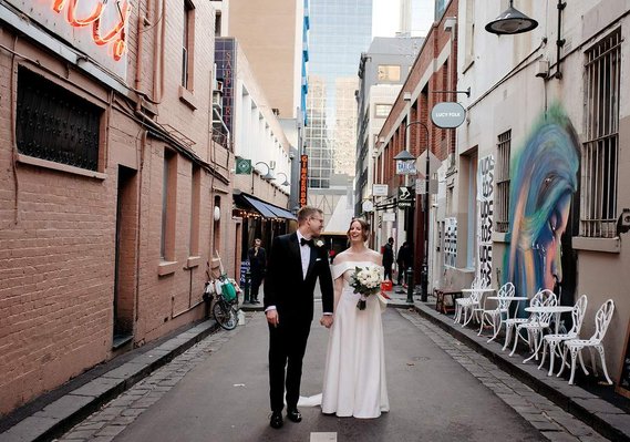 couple holding hands. woman has flowers in hand. walking in a ally way