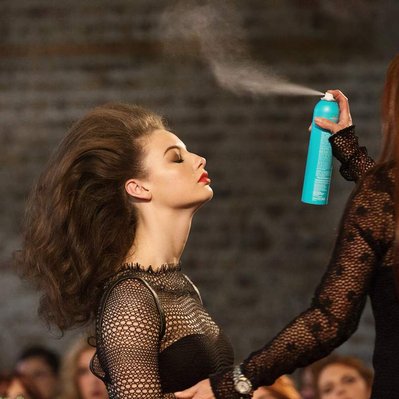 Model getting sprayed with Moroccan oil hairspray in a blue branded bottle at a live customer event in Dublin, Ireland. Taken by a professional corporate event photographer www.eventimage.ie