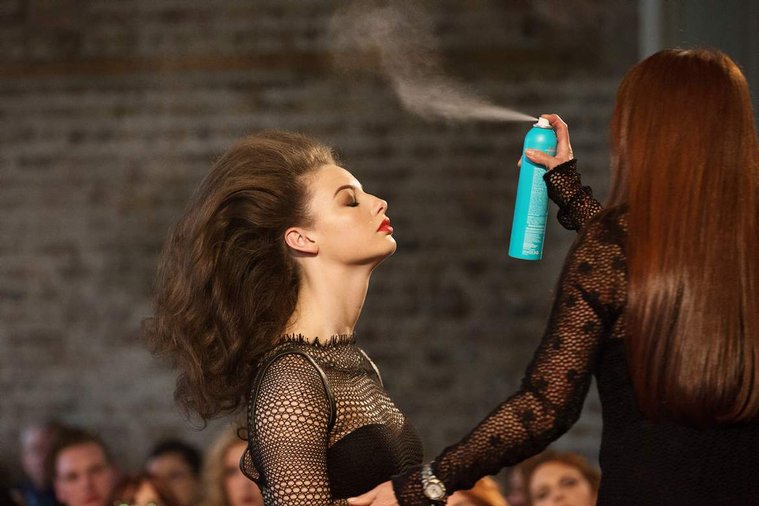 Moroccanoil salon owners live event in Dublin, model tilts her head back while stylist sprays from a can of moroccanoil hairspray in front of live audience professional event photographer 