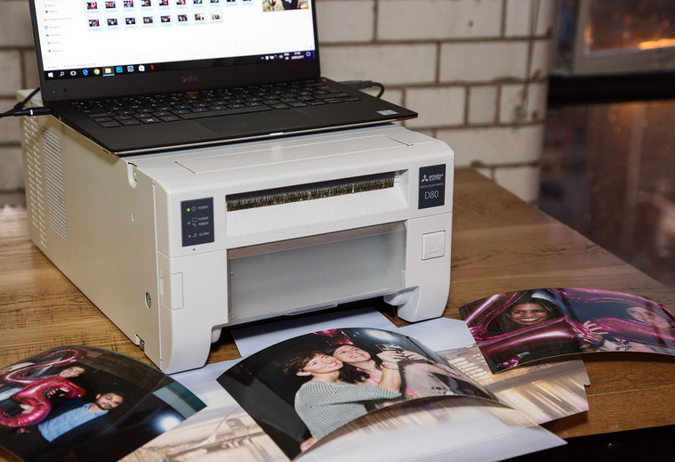 Onsite printing for live events. Professional photo of laptop and printer with hard copy prints of branded photo memento gifts for attendees. Event photographer Dublin