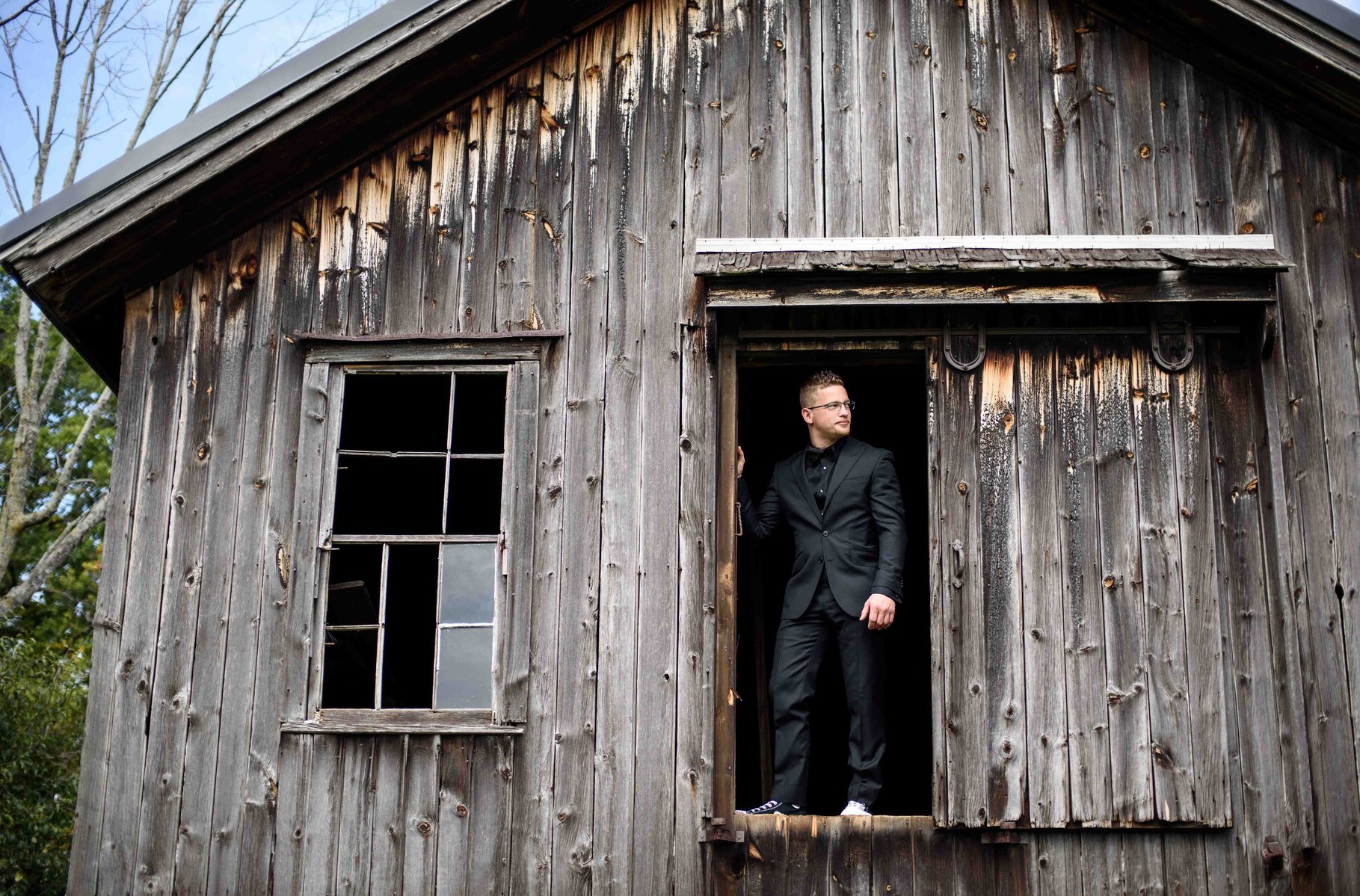 Cobblestone Wedding Barn photo - Groom standing in an opening in the barn