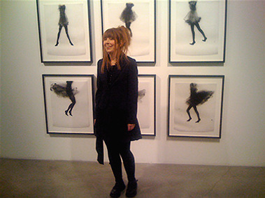Photo of Cathy Daley at gallery exhibition standing in front of her drawings.