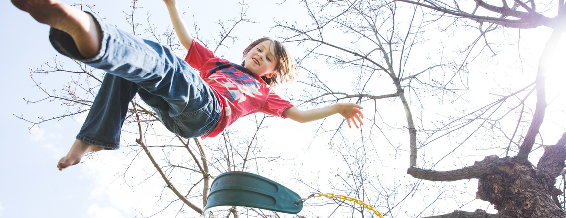 Child in the air having jumped off a swing hanging from a tree