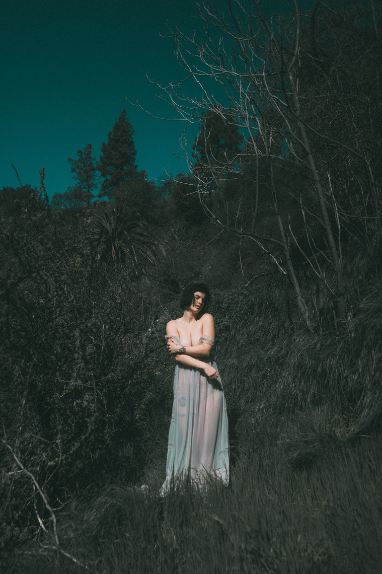 Woman stands on hillside wearing vintage dress