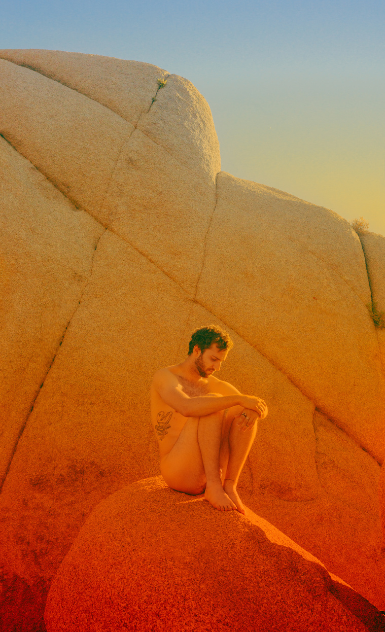 Colorful vintage film nude of man sitting on rocks at Joshua Tree National Park