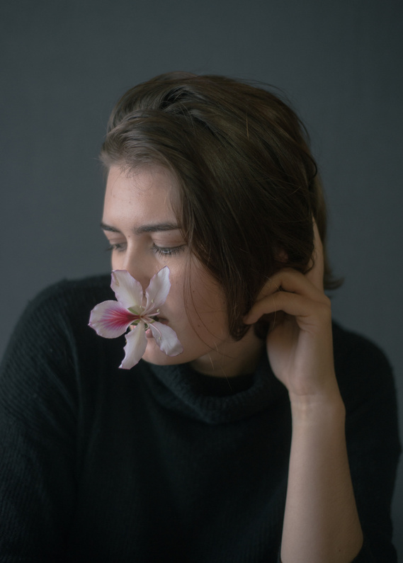 Portrait of woman with orchid flower in her mouth