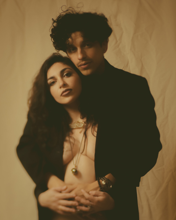 Vintage film studio portrait of couple embracing against cloth backdrop