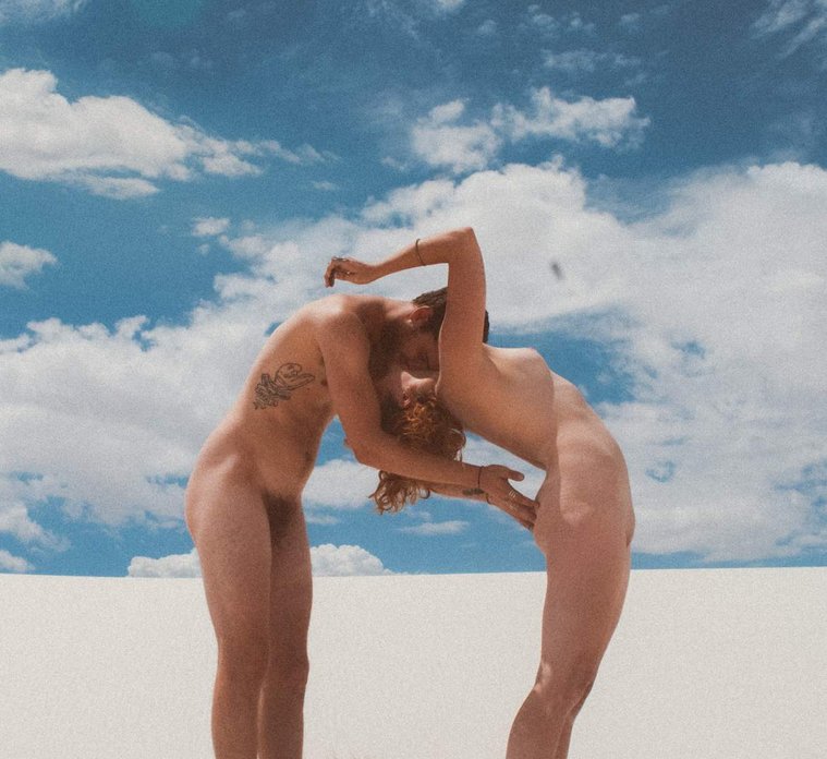 Vintage film nude of couple against blue cloudy skies in White Sands, New Mexico