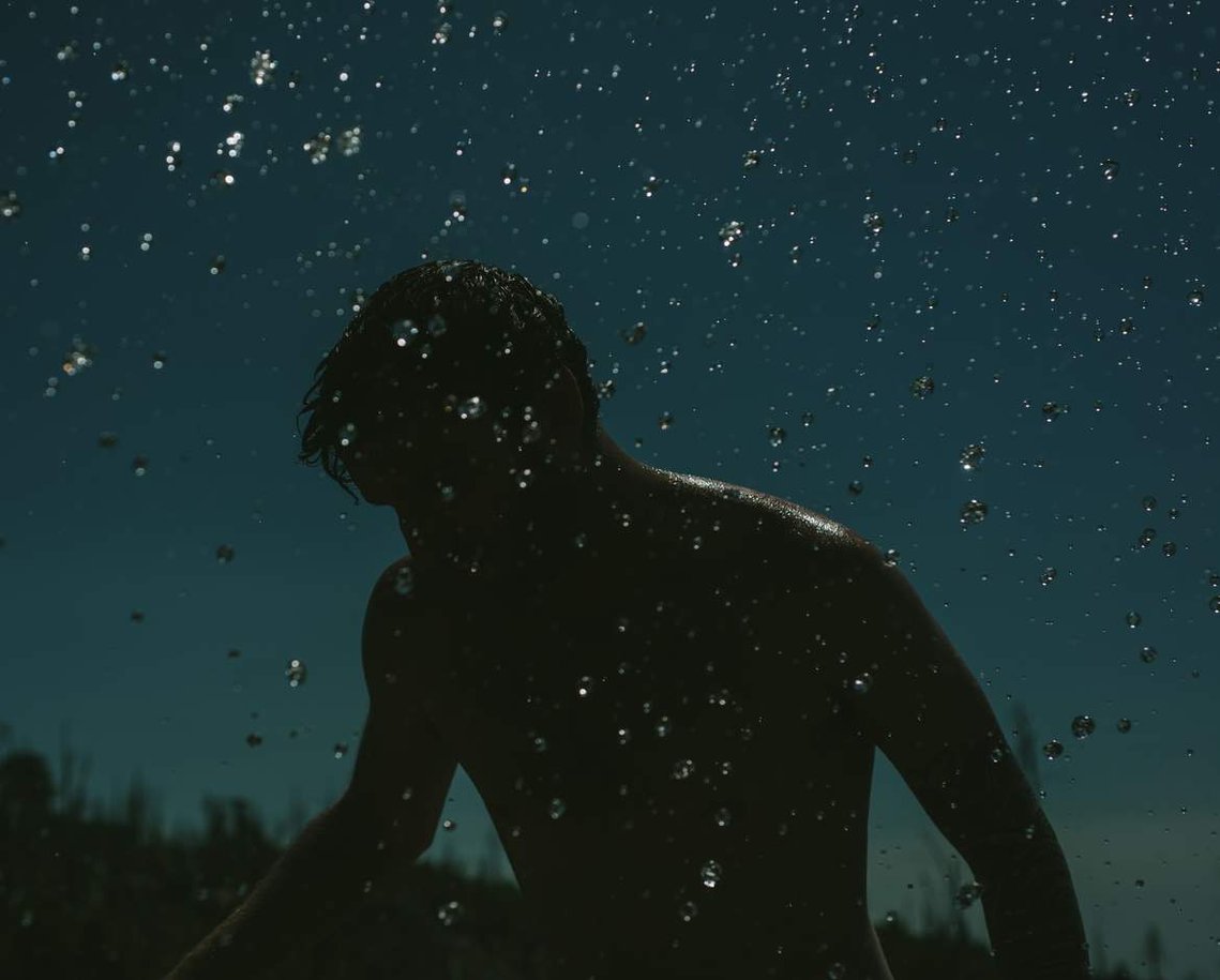 Silhouette of man and drops of water against blue sky