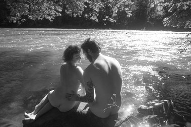 Couple sits on rock next to river in Olympic National Park, Washington