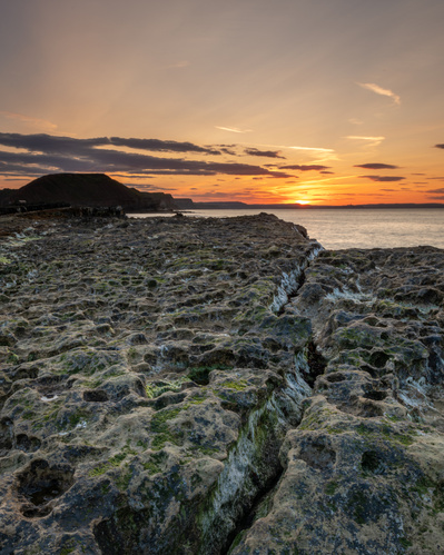 The sun sets beyond Scarborough in this image of Filey Brigg and its rock formations. A photograph by Tim Pearson.