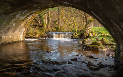 A small cascade on Oxnop Beck in Swaledale, Yorkshire Dales National Park, framed by a bridge. A photograph by Tim Pearson.