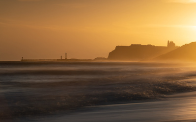 Whitby viewed from dawn sunlight from Sandsend, North Yorkshire. A photograph by Tim Pearson