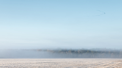 A skein of geese flies over frozen fields and woodland in East Yorkshire. One of the Hibernal series of photographs by Tim Pearson.