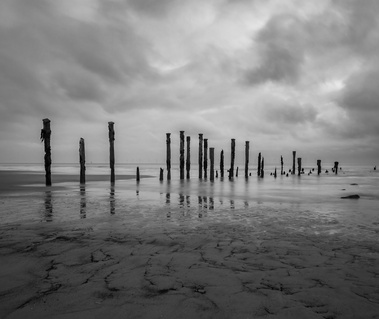 Coastal groynes under the moody sky at Spurn Point Nature Reserve, East Yorkshire, UK. A monochrome image by Tim Pearson.