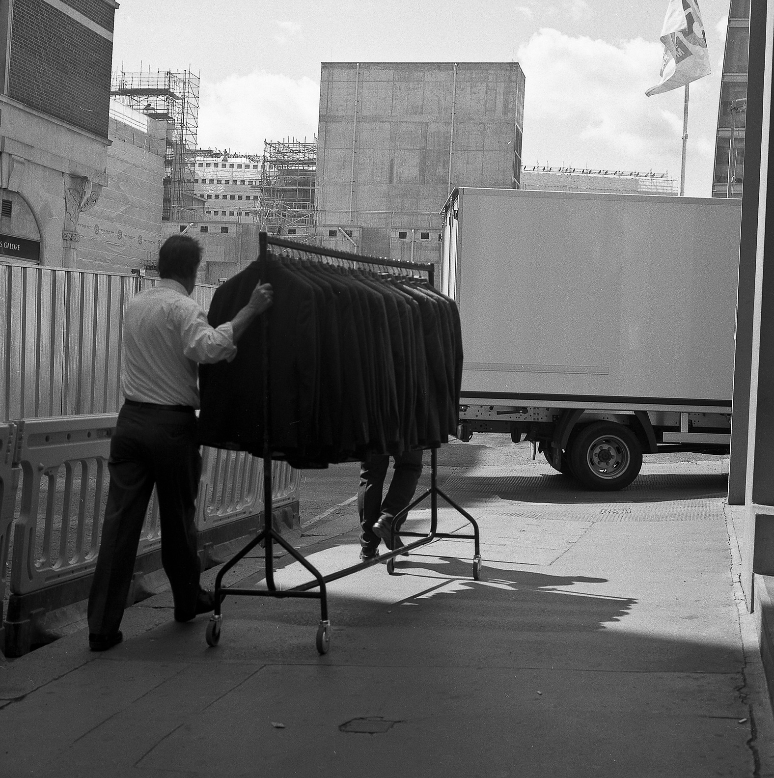 Two men push a rail of coats