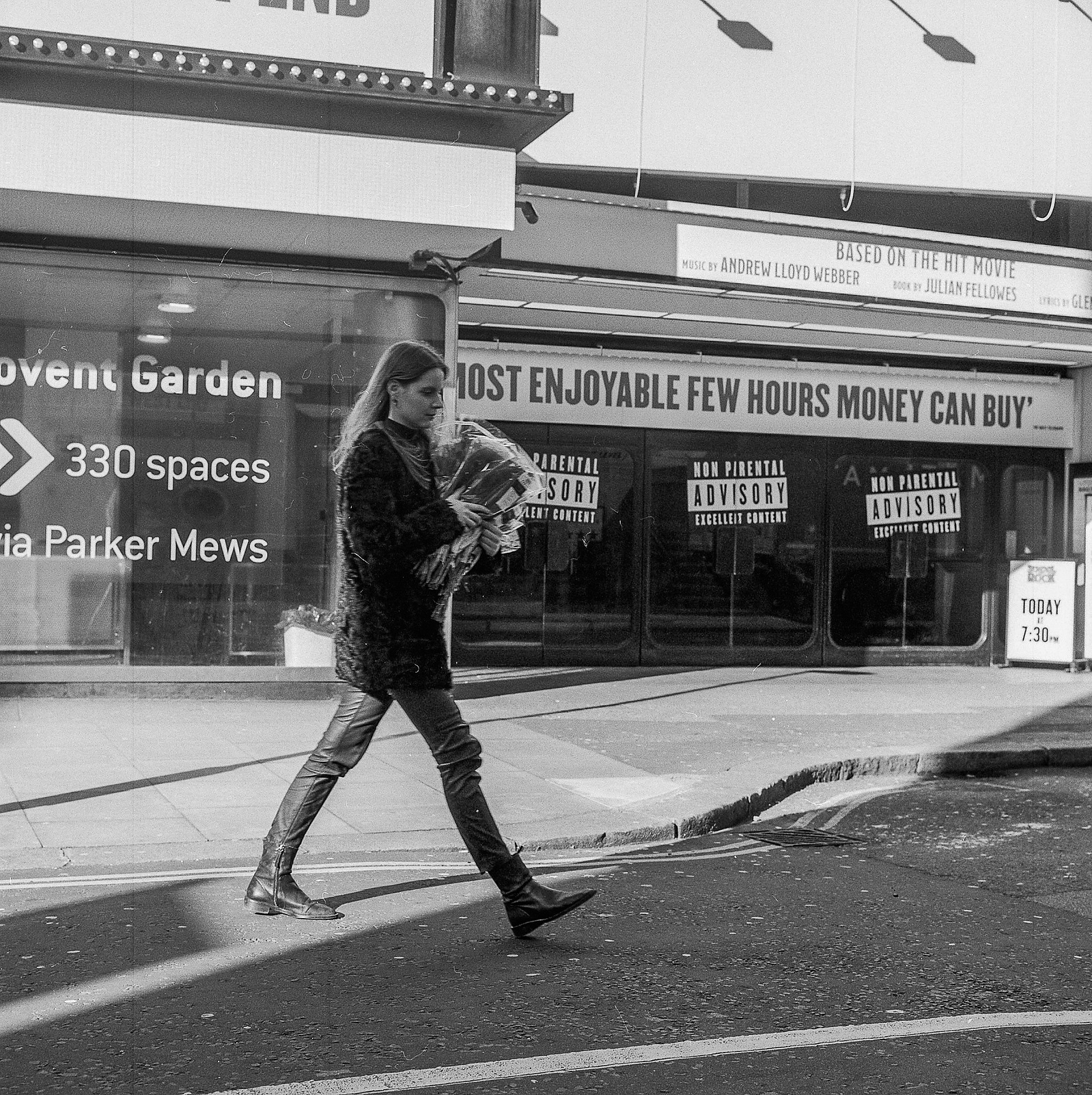 A woman carries roses past a theatre