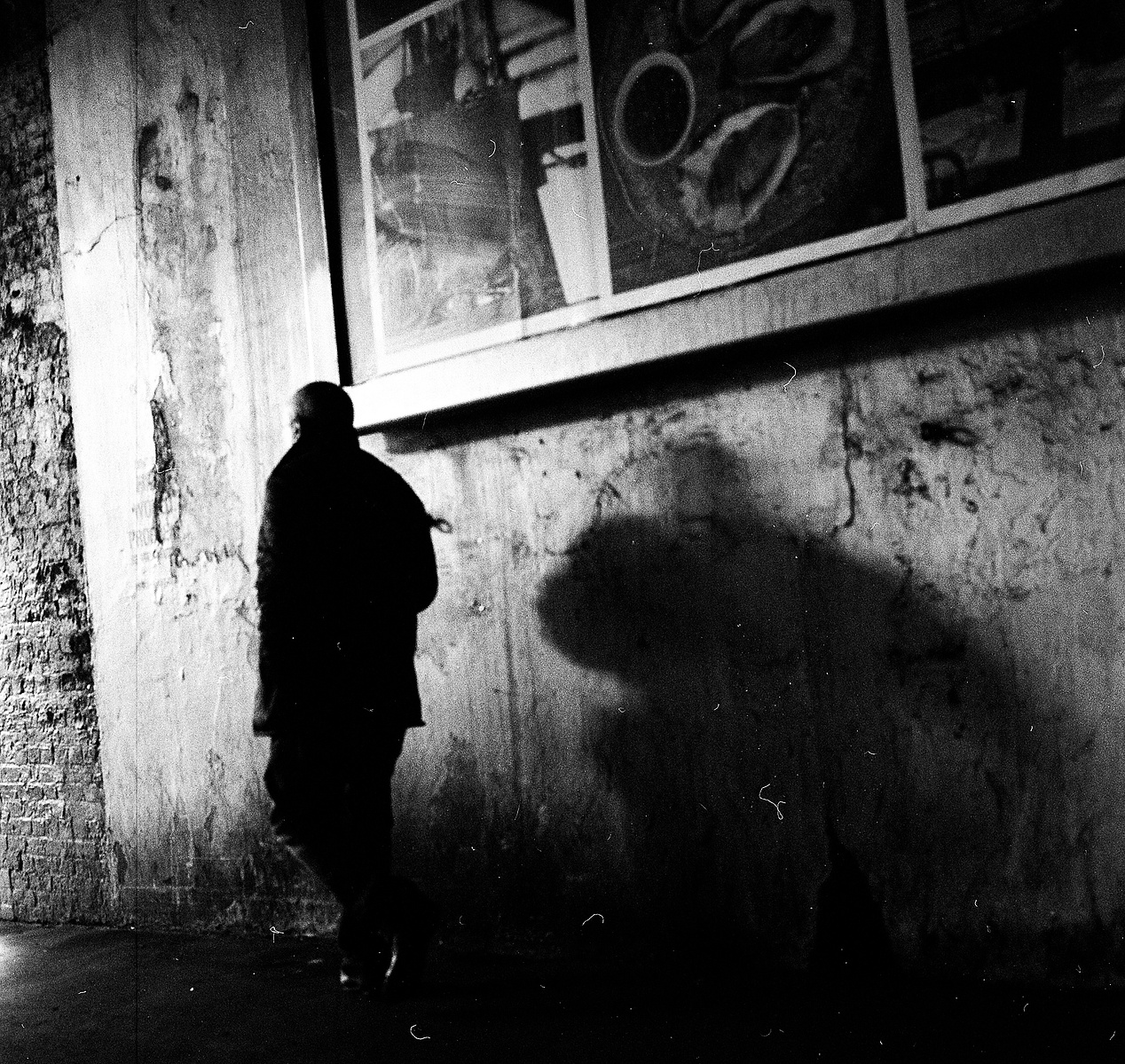 A shadow cast by a man passing a billboard