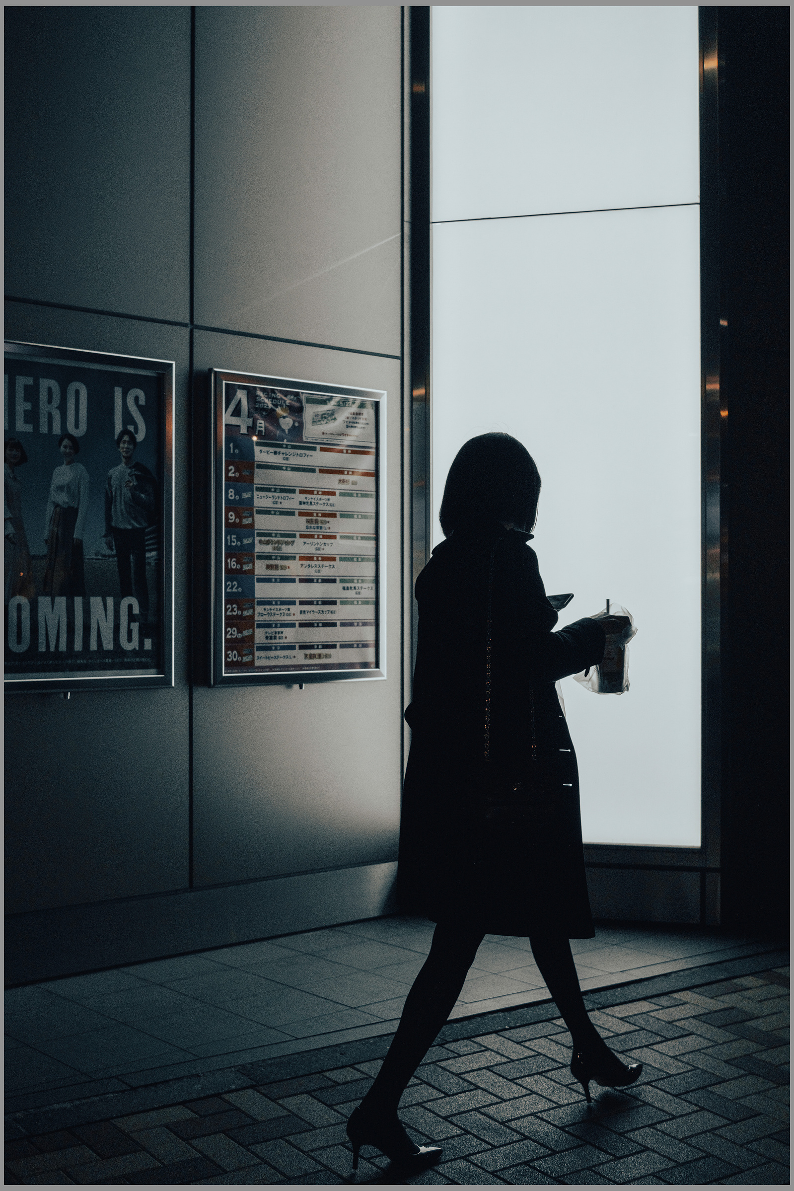A woman silhouetted as she passes the camera at night