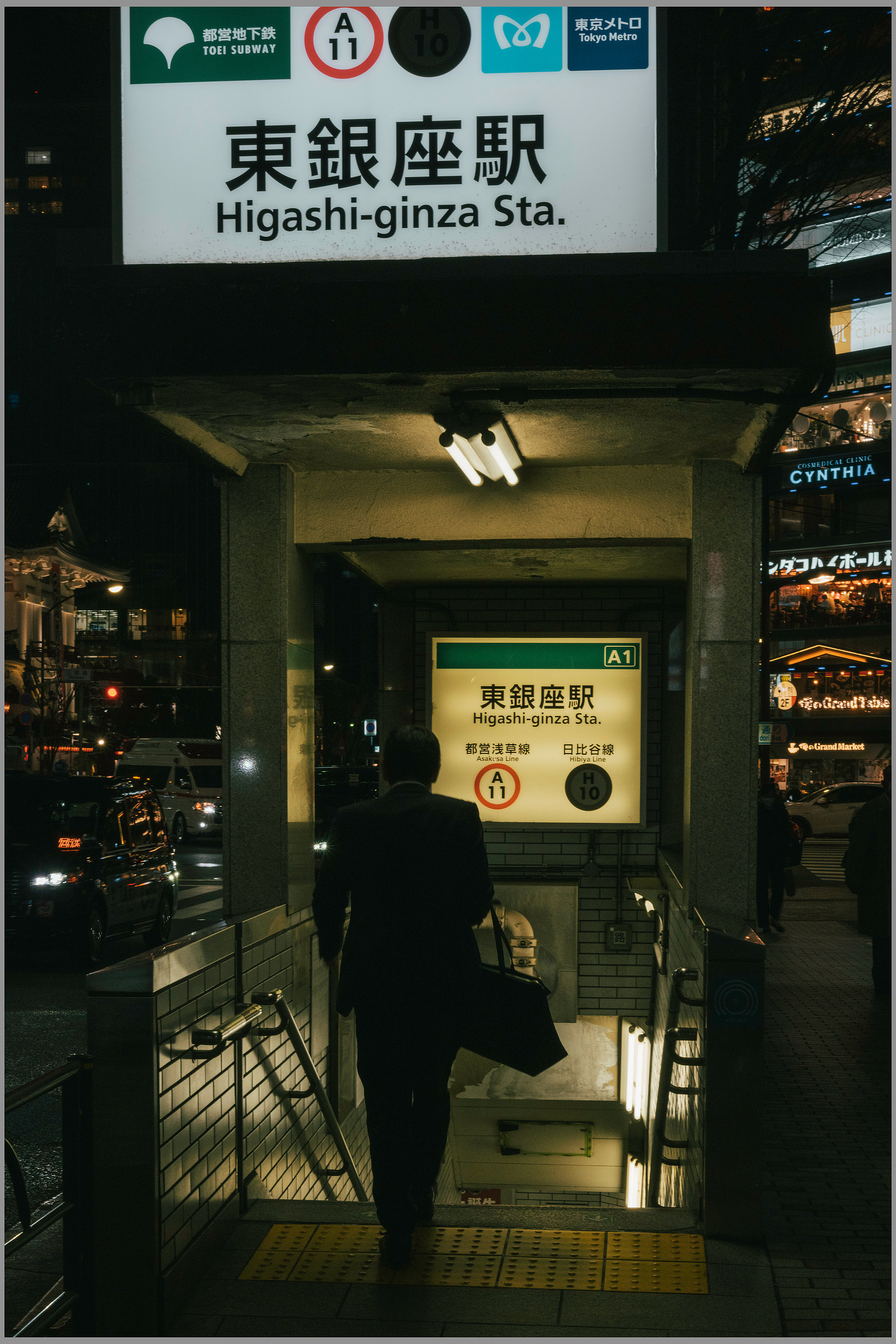 A man taking the stairs down into a train station at night