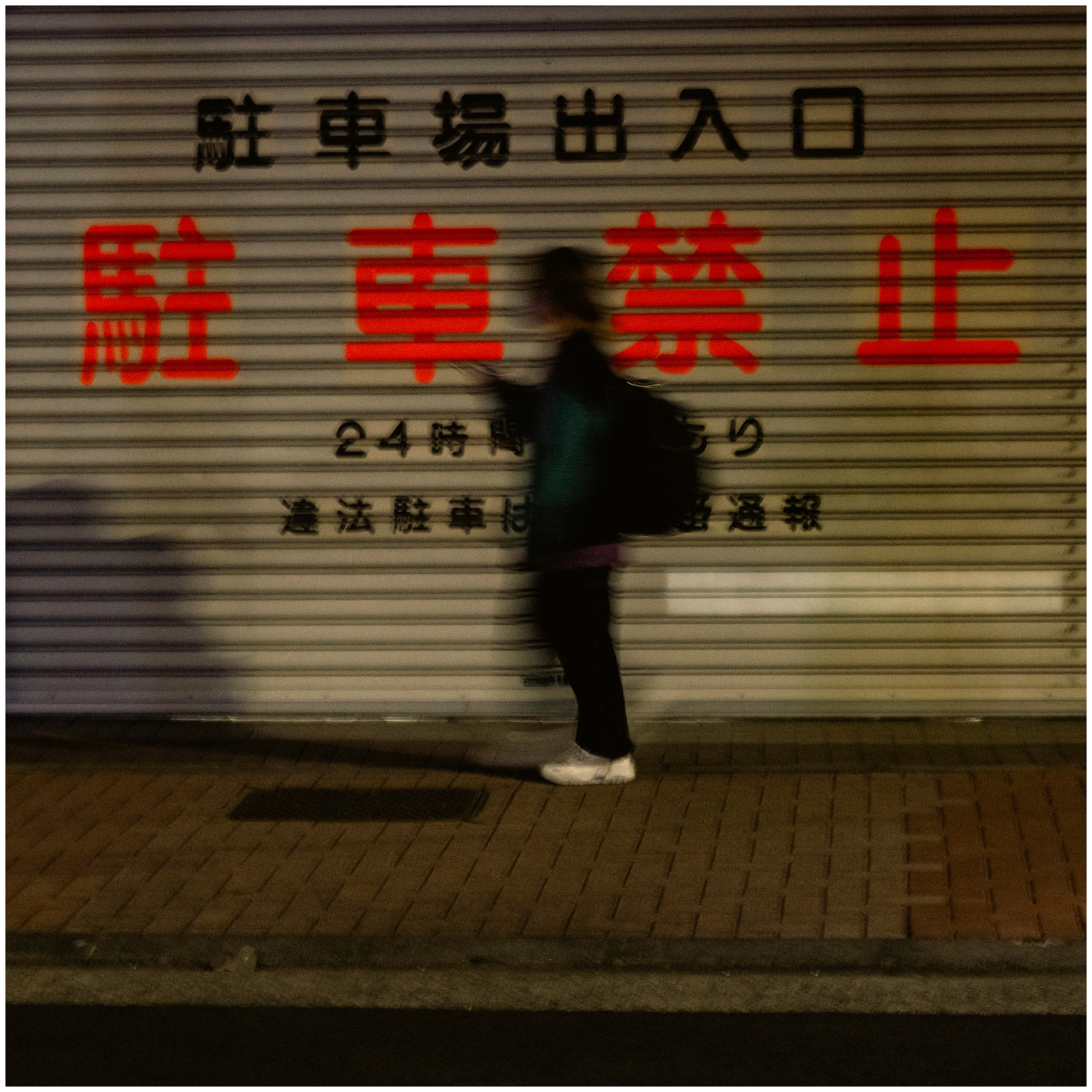 A figure walking past some signs at night