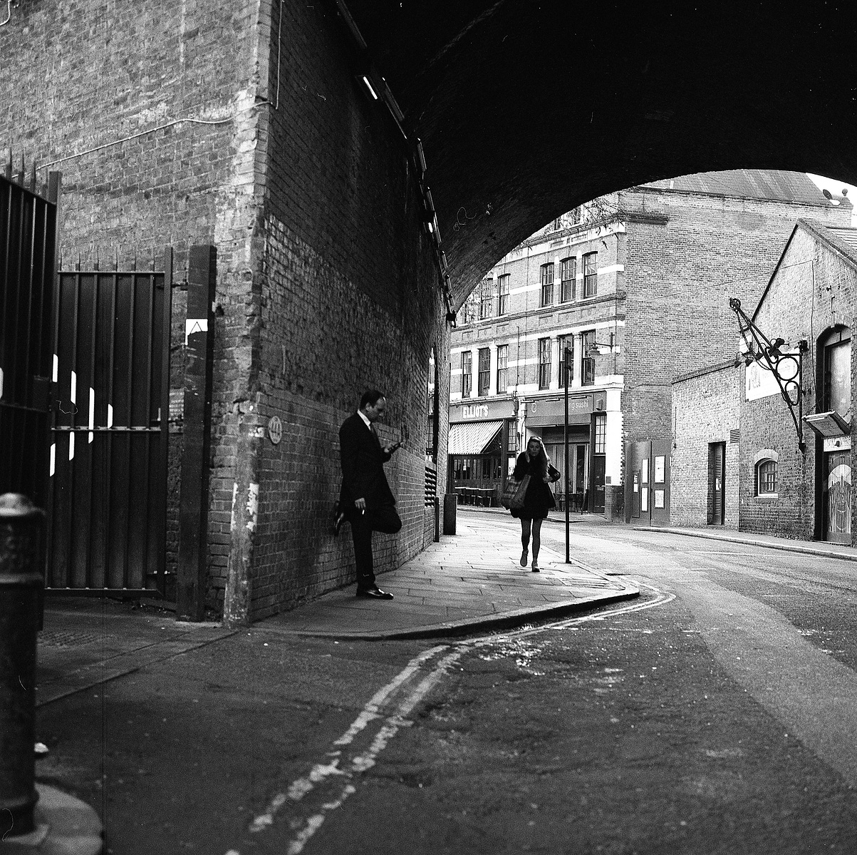 A man smokes leaning on a wall