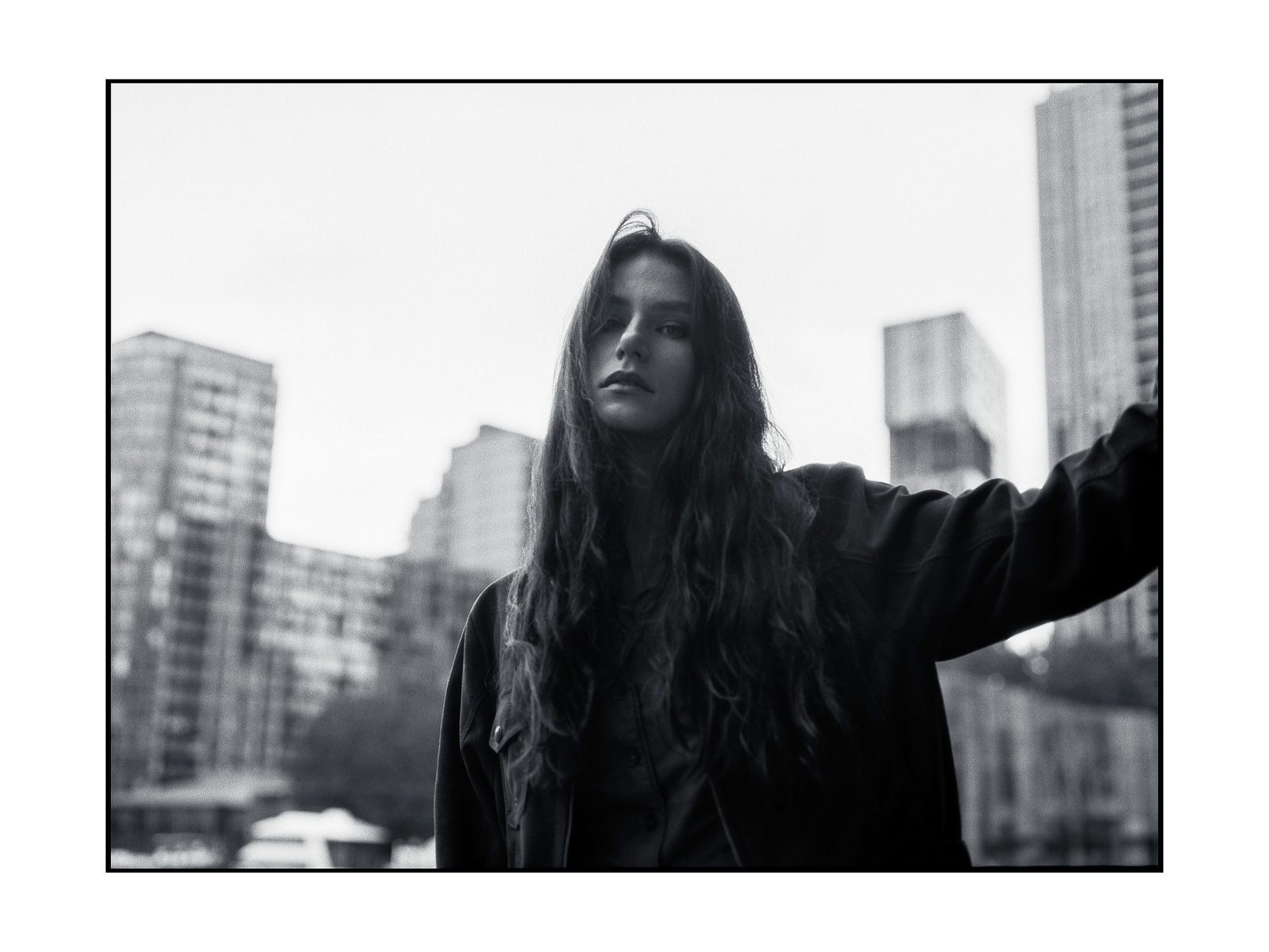 Woman standing - cityscape behind her blurred with depth of field. Black and white.