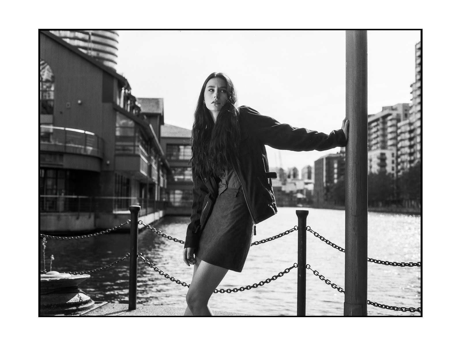 woman leaning on a post. there is a river behind her.