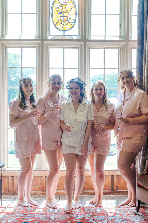 relaxed wedding photography, bride and bridesmaids in pyjamas, group shot in front of stately home window