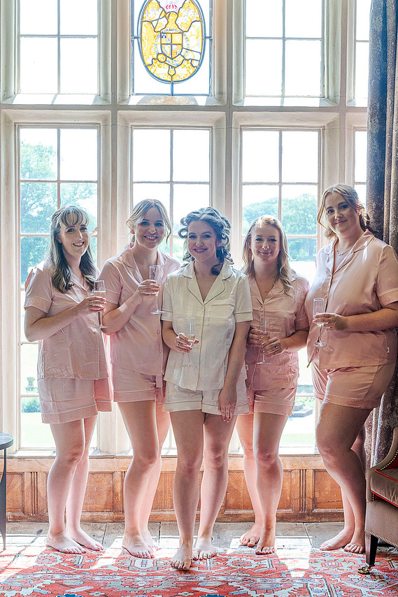 relaxed wedding photography, bride and bridesmaids in pyjamas, group shot in front of stately home window