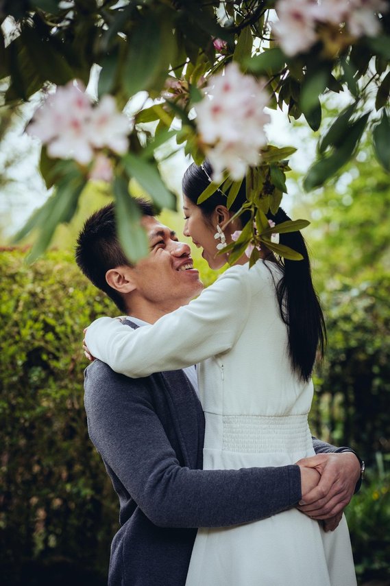 candid and natural wedding photography, city centre urban wedding, wedding couple, engagement shoot, couple hugging and laughing under blossom trees