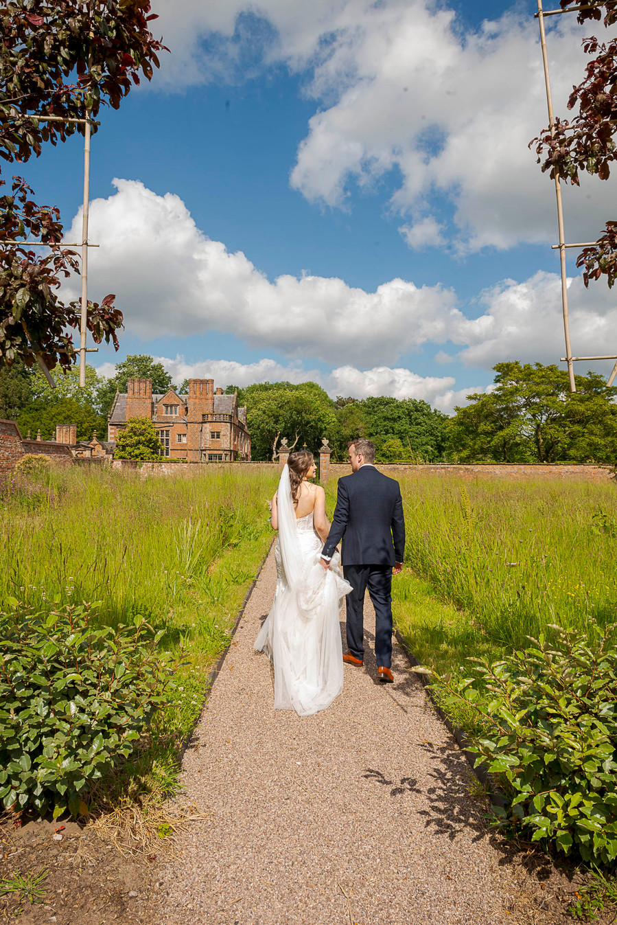 natural and authentic wedding photography, bride and groom walking away from camera through gardens
