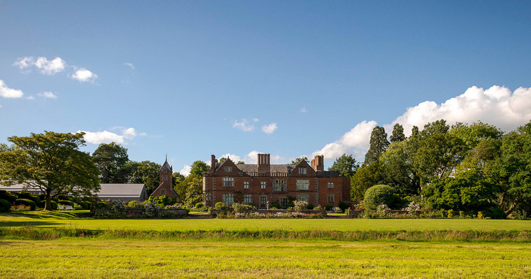 natural and relaxed wedding photography, photo of Dorfold hall in Cheshire, wide shot with gardens in foreground and blue sky with clouds