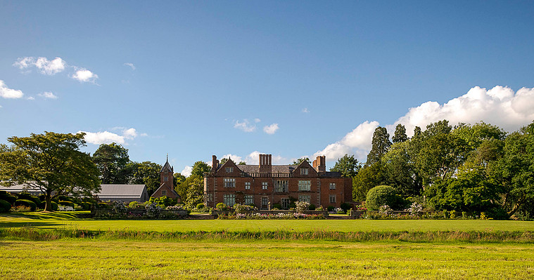 natural and relaxed wedding photography, photo of Dorfold hall in Cheshire, wide shot with gardens in foreground and blue sky with clouds