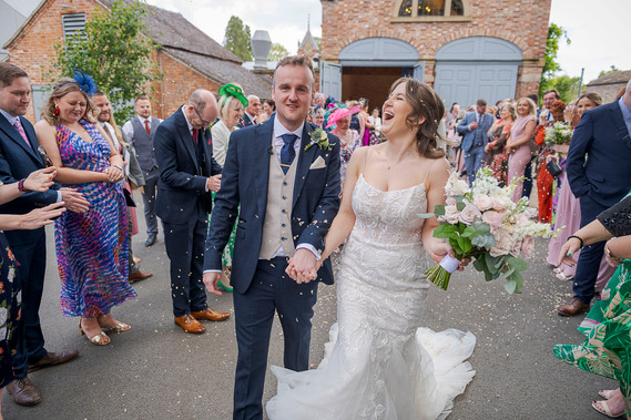 relaxed wedding photography, candid shot of bride and groom walking past guests as they throw confetti