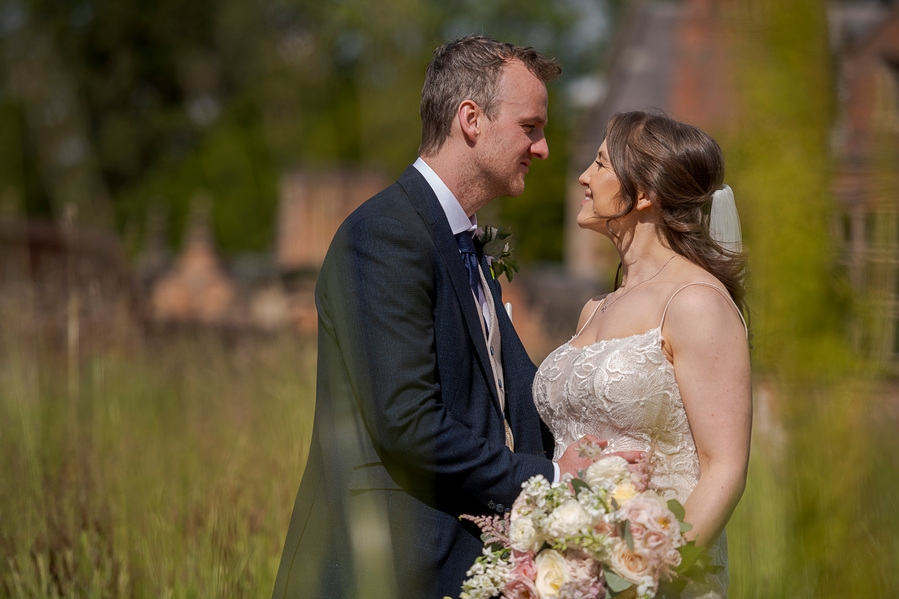 natural and authentic wedding photography, bride and groom look at each other about to kiss, long grass in foreground
