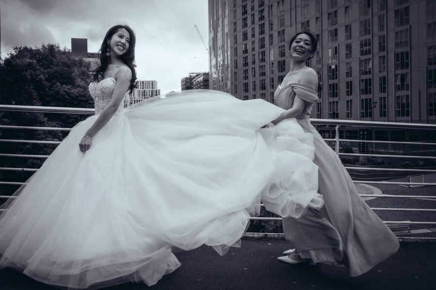candid and natural wedding photography, city centre urban wedding, bridesmaid holds bride's flowing dress