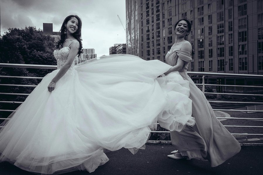 candid and natural wedding photography, city centre urban wedding, bridesmaid holds bride's flowing dress