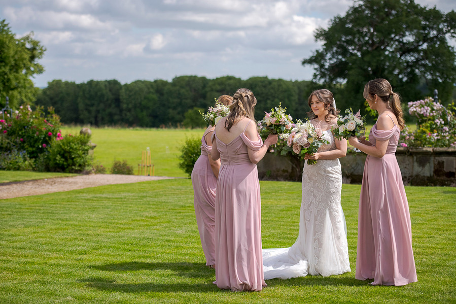 bride and bridesmaids stood in circle in gardens