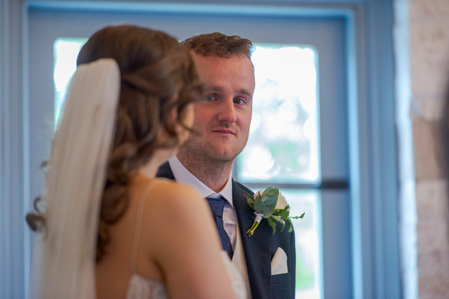 natural and authentic wedding photography, groom looks at bride during ceremony
