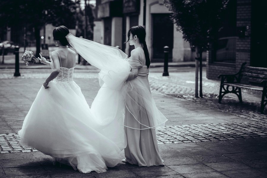 candid and natural wedding photography, city centre urban wedding, bride and bridesmaid in black and white, wind blows brides veil