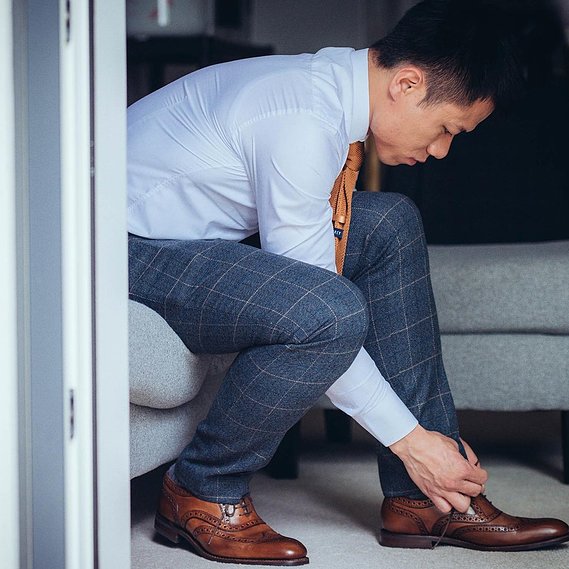 candid and natural wedding photography, city centre urban wedding, groom getting ready and tying shoelaces