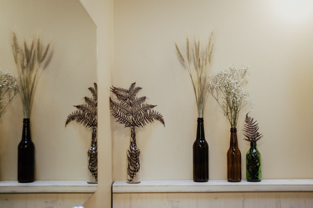 Détail de décoration dans le restaurant Orta à Bordeaux. Fleurs séchées, mirroir et bouteilles en verre.
