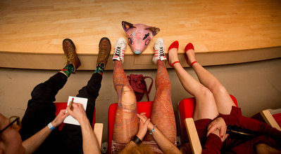 A view of 3 peoples legs & feet seated at an artist talk at the Madison Museum of Contemporary Art. 